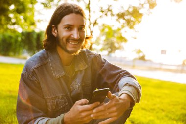Gülümseyen genç adam cep telefonu tutarak