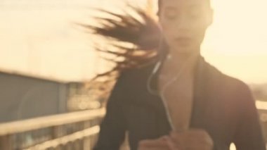 Kulaklıklı, müzik dinleyen ve açık havada koşan konsantre Asyalı güzel bir spor kadınının yakın görüntüsü.