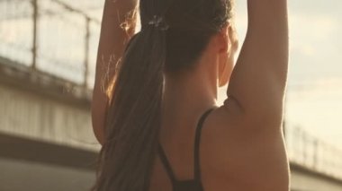 Kulaklık takan, müzik dinleyen ve elleri dışarıda esneyen Asyalı güzel bir spor kadının yakın görüntüsü.