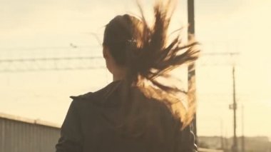 Kulaklıklı, müzik dinleyen ve açık havada koşan Asyalı güzel bir kadının arka görüntüsü.