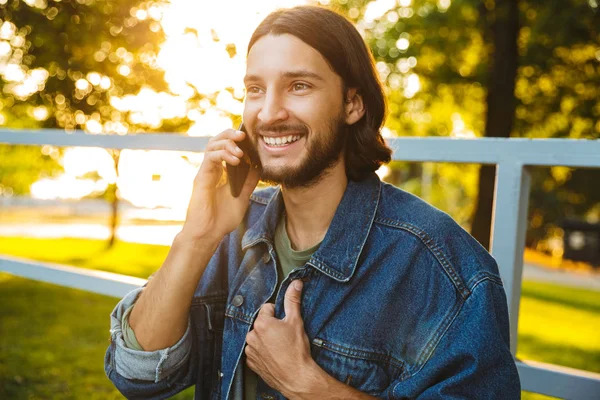 Χαμογελαστός νέος άνθρωπος κρατώντας κινητό τηλέφωνο — Φωτογραφία Αρχείου