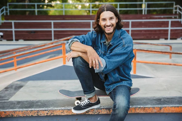 Attractive young hipster man sitting at the skate ramp — Stock Photo, Image