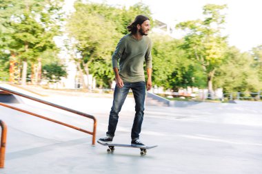 Yakışıklı genç hippi kaykay rampasında kayıyor.