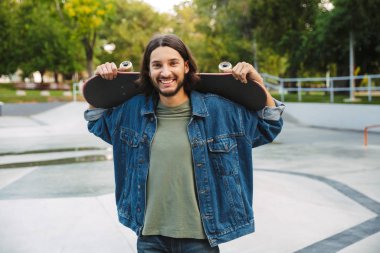 Çekici genç hippi kaykay rampasında oturuyor.