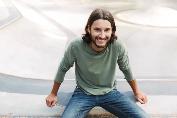 Attractive young hipster man sitting at the skate ramp — Stock Photo, Image