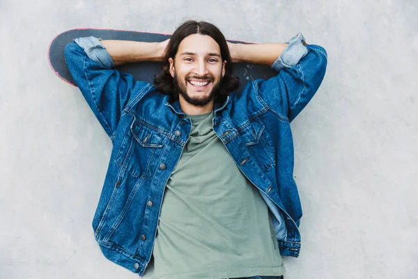 Visão superior de um jovem sorridente deitado em um skate — Fotografia de Stock