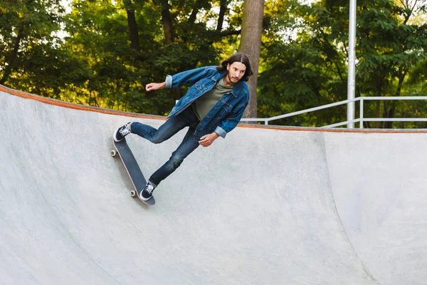 Bonito jovem hipster patinando em uma rampa de skate — Fotografia de Stock