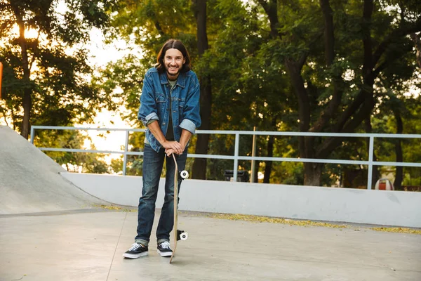 Aantrekkelijke jonge hipster man zittend aan de skate helling — Stockfoto