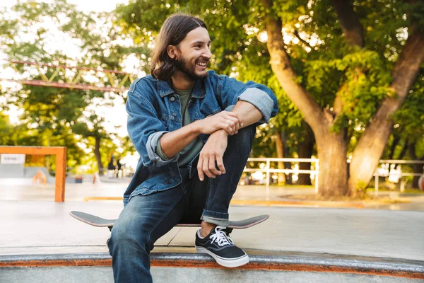 Attraente giovane hipster seduto alla rampa di pattinaggio — Foto Stock