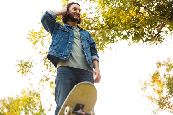 Schöner junger Hipster-Mann beim Schlittschuhlaufen auf einer Skaterrampe — Stockfoto