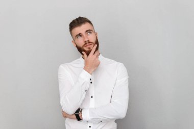 Sakallı ciddi bir adamın görüntüsü yukarı bakıyor ve düşünüyor.