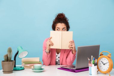Kafası karışmış bir kadının kitap tutuşu ve çalışırken yana bakışı.