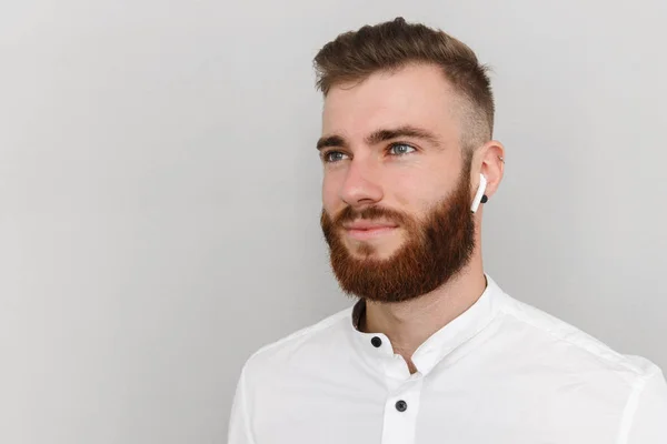 Bild av ung stilig man med skägg poserar och använder hörselkåpa — Stockfoto