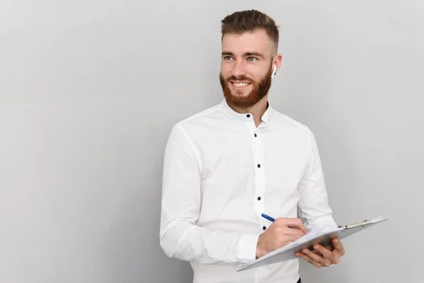 Imagem de homem bonito alegre sorrindo ao escrever e usar o fone de ouvido — Fotografia de Stock