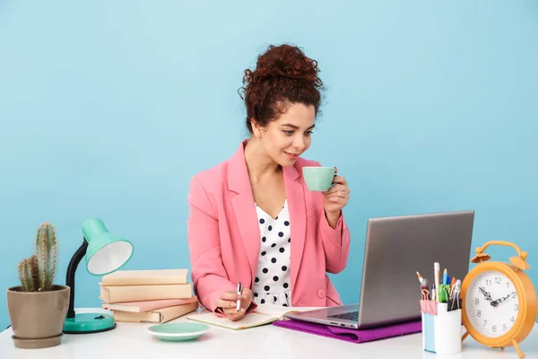 Εικόνα ελκυστικής γυναίκας που χρησιμοποιεί φορητό υπολογιστή και πίνει καφέ ενώ εργάζεται — Φωτογραφία Αρχείου