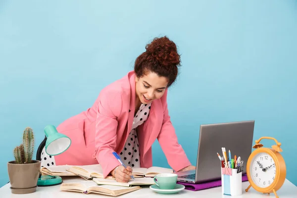 Immagine di una donna contenta che prende appunti nel diario mentre lavora alla scrivania — Foto Stock