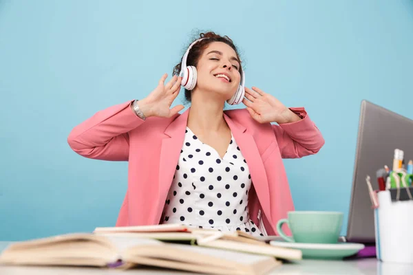 Obraz szczęśliwej młodej kobiety słuchającej muzyki ze słuchawkami podczas pracy — Zdjęcie stockowe