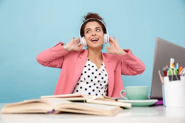 Imagem de mulher sorridente ouvindo música com fones de ouvido enquanto trabalhava — Fotografia de Stock