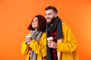 Sarı yağmurluklarla poz veren sevgili çift izole edilmiş.