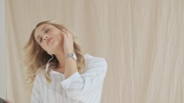 Güzel sarışın bir kadın dans ediyor. Kumaş arka planda izole edilmiş telli kulaklıklarla müzik dinliyor.