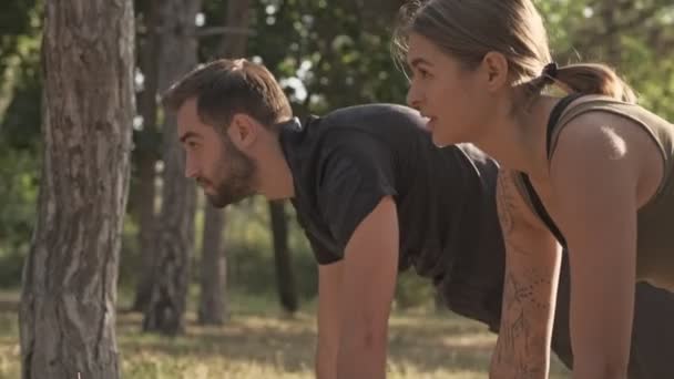 聚精会神的年轻夫妇在户外公园一起做跳板运动的侧视图 — 图库视频影像