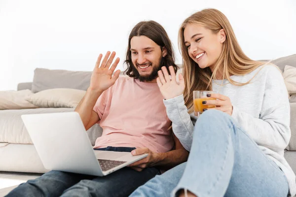 Loving couple near sofa using laptop computer — 스톡 사진