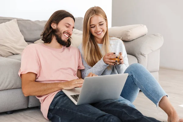 Loving couple near sofa using laptop computer — 스톡 사진
