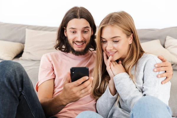 Любящая пара на диване дома с помощью мобильного телефона . — стоковое фото