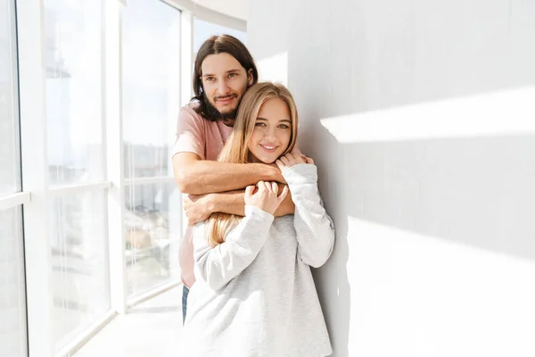 Schönes schönes Paar, das im Wohnzimmer am Fenster steht — Stockfoto