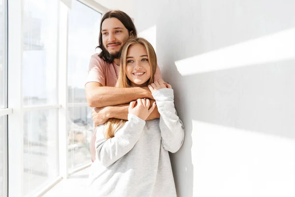 Schönes schönes Paar, das im Wohnzimmer am Fenster steht — Stockfoto