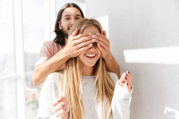 Hermosa pareja encantadora de pie en la sala de estar en la ventana —  Fotos de Stock