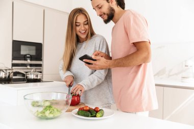 Mutfaktaki sevgili çift cep telefonu kullanıyor.