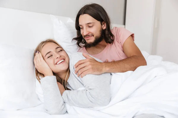 Güzel genç çift yatakta döşeme — Stok fotoğraf