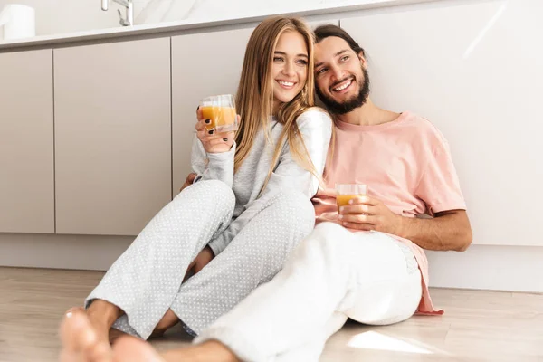 Usmívající se krásný pár objímající zatímco sedí na podlaze v kuchyni — Stock fotografie
