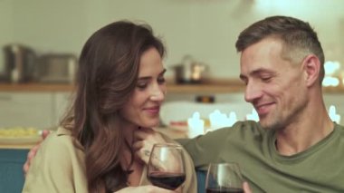 Mutlu çift evde mumlarla romantik bir ortamda şarap içiyor.