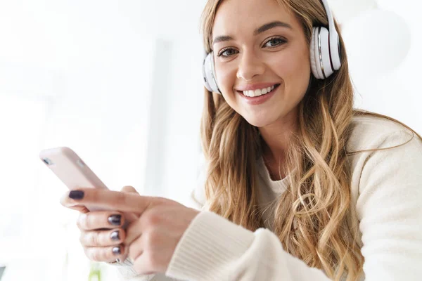 Photo of young smiling woman using headphones and cellphone — Stock Photo, Image