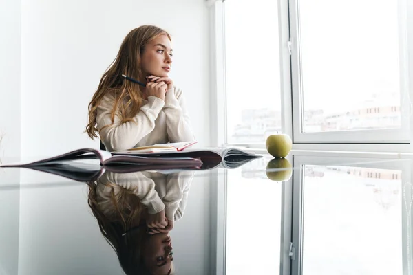 Foto de una joven mujer pensante mirando a la ventana y tomando notas — Foto de Stock