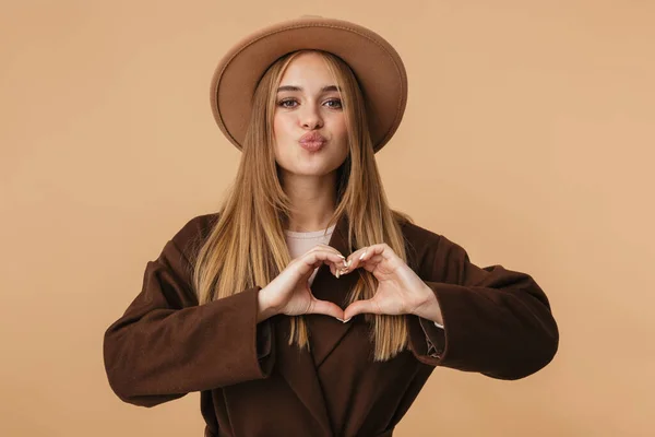 Imagen de una chica joven con sombrero sonriendo y mostrando la forma del corazón — Foto de Stock