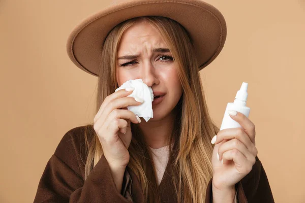 Образ хворої кавказької дівчини, що тримає краплі носа та паперову серветку — стокове фото