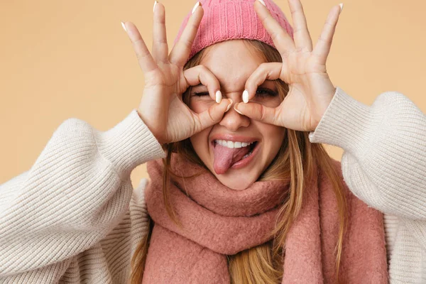 Image of young girl in winter hat looking through fingers binocu — Stock Photo, Image