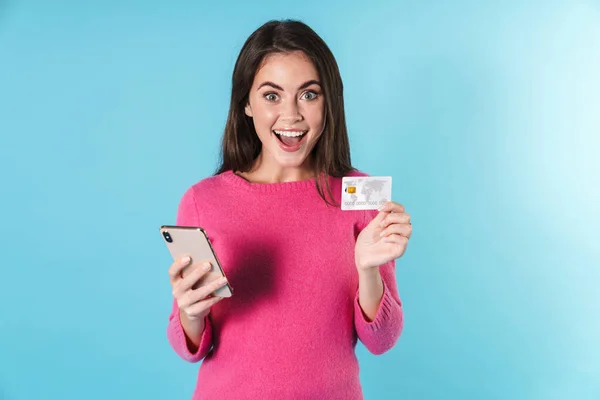 Foto de mulher sorrindo digitando no celular e segurando cartão de crédito — Fotografia de Stock