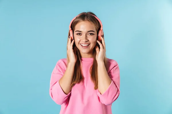 Foto de mulher encantada sorrindo e ouvindo música com fones de ouvido — Fotografia de Stock