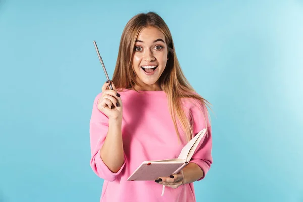 Foto van een verrassende vrouw glimlachend terwijl het vasthouden van notebook en potlood — Stockfoto