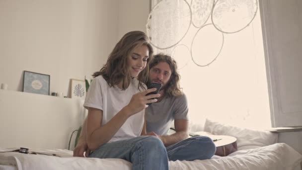 Härligt Par Med Smartphone Och Glädjas Efter Det Medan Sitter — Stockvideo