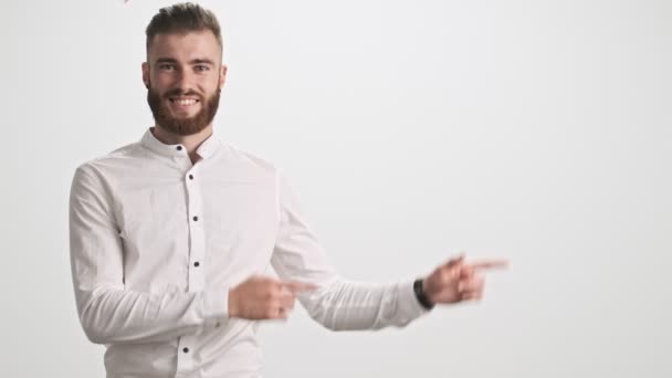 Jovem Barbudo Positivo Vestindo Uma Camisa Branca Está Apontando Para — Vídeo de Stock