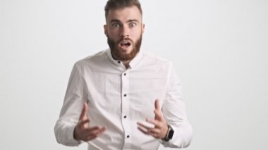 Şaşırtıcı bir şekilde genç sakallı bir adam beyaz duvar arkasında izole edilmiş kameraya bakıyor.