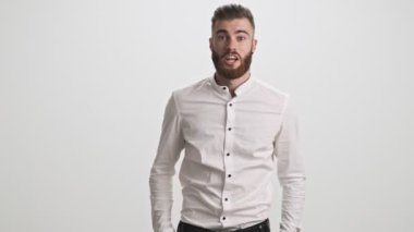 Mutlu, çığlık atan sakallı bir adam, iki eli beyaz duvar arkasında izole bir şekilde kazanan bir jest yapıyor.