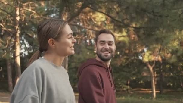 Vista Lateral Casal Bonito Jovem Satisfeito Falando Divertindo Enquanto Caminham — Vídeo de Stock