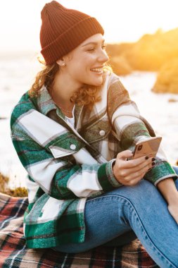 Kafkas kadının akıllı telefon kullanması ve otururken gülmesi.
