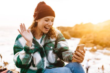 Akıllı telefon kullanan ve el sallayan heyecanlı bir kadın görüntüsü